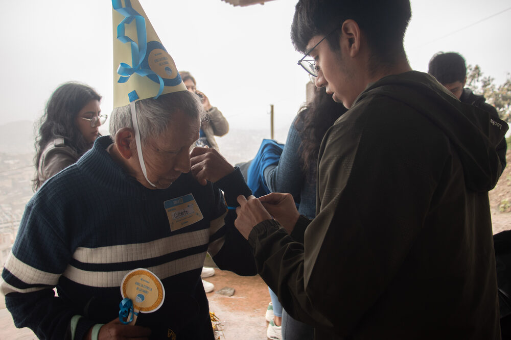 Voluntario joven ayuda a adulto mayor en lectura individual durante el evento
