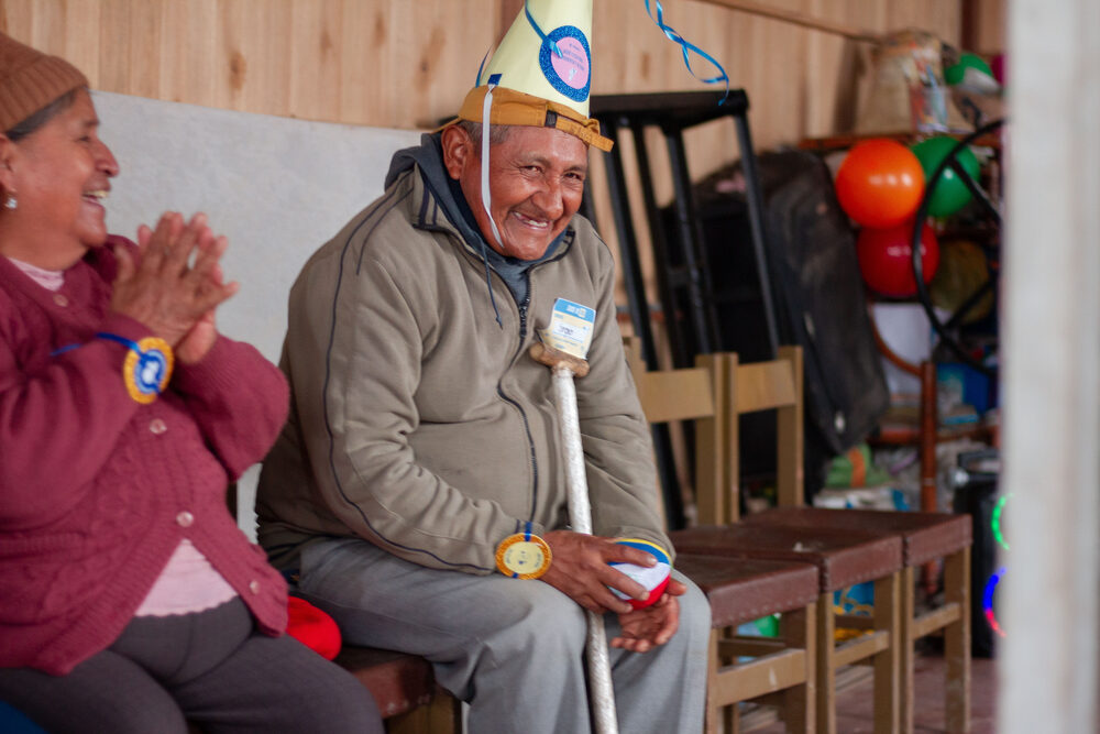 Pareja de adultos mayores con gorros de fiesta riendo durante celebración