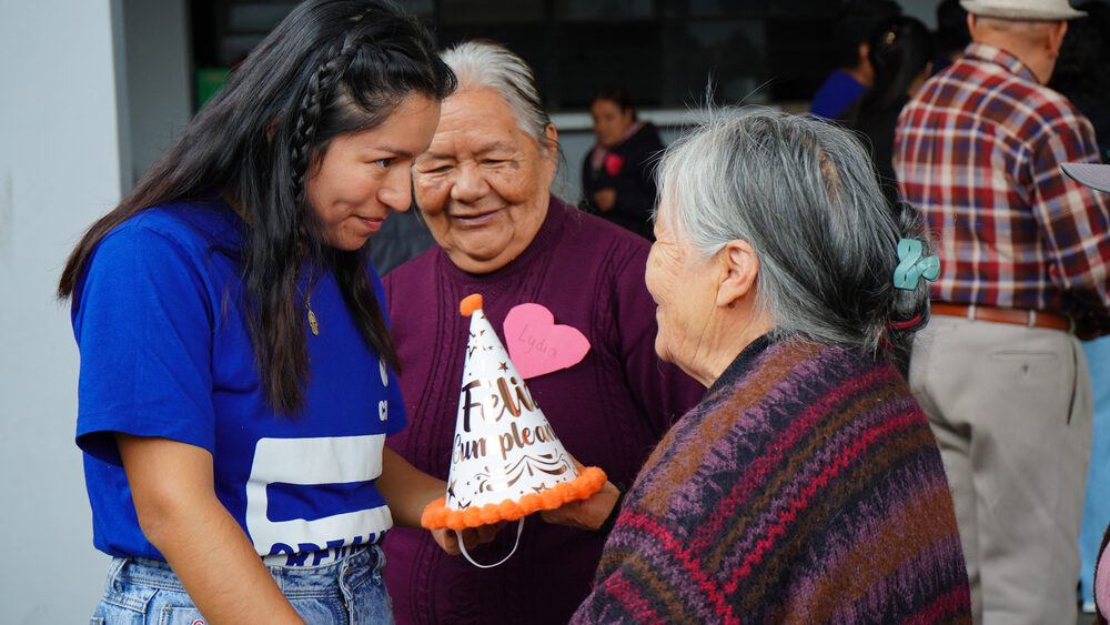 Voluntaria abraza con cariño a dos adultas mayores durante cierre del taller