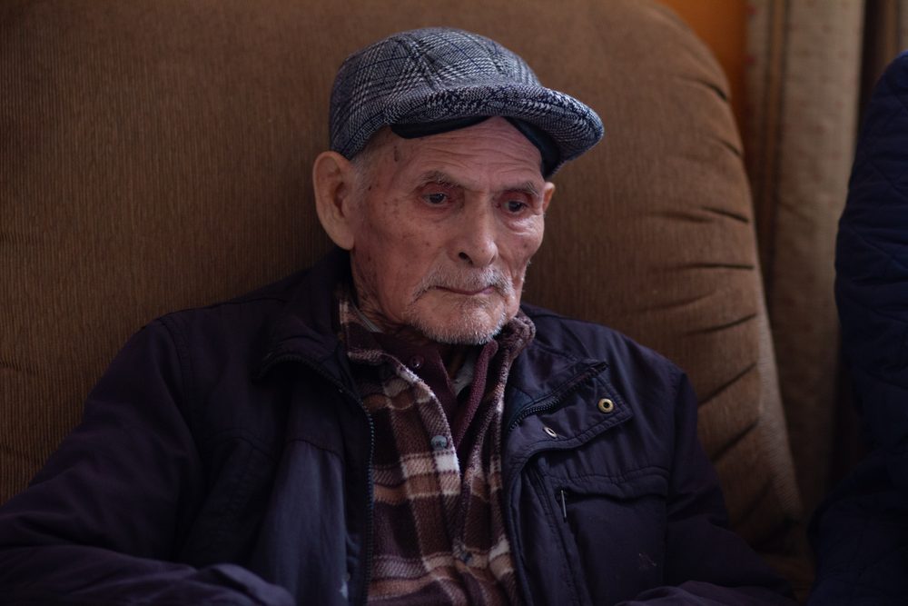 Retrato de adulto mayor varón con gorra escocesa, mirada digna y serena