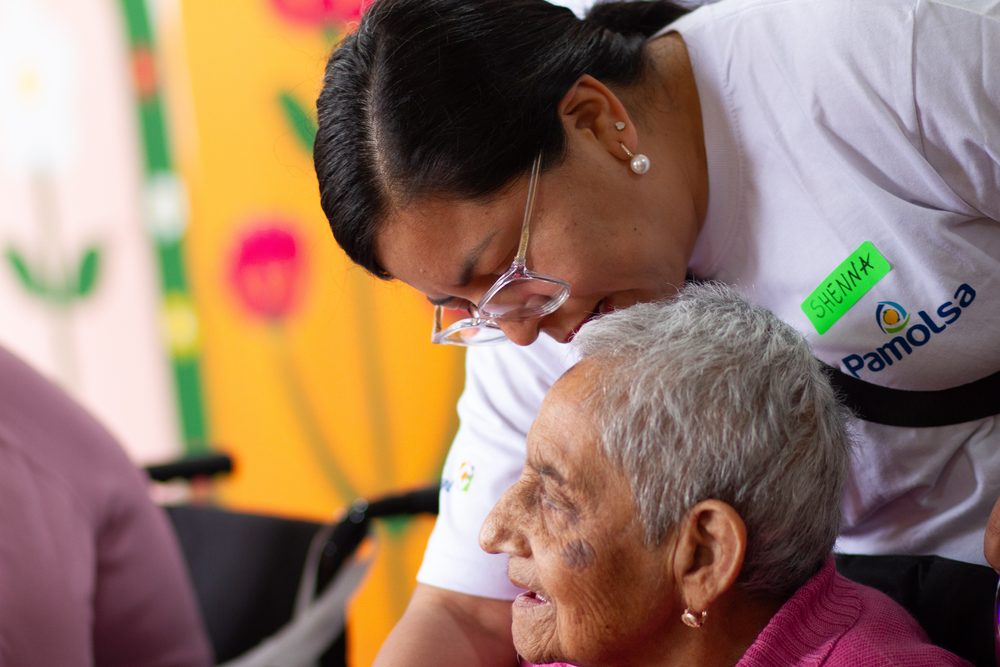 Voluntaria abraza con ternura a adulta mayor canosa durante visita al albergue